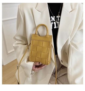 Close-up of yellow woven mini bag with rounded handles and matching shoulder strap