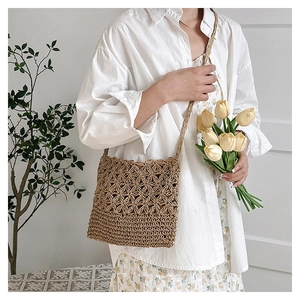 Détail du motif floral géométrique tissé à la main sur un sac de plage en paille marron