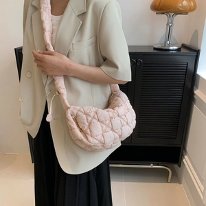 Pink quilted puffer crescent bag with padded shoulder strap shown on model in soft light