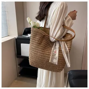 Detail of large straw tote bag with brown leather handles and white lace floral scarf