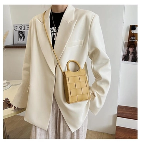 Detail of yellow woven mini bag with Intrecciato craft on beige blazer outfit