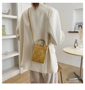 Mini yellow woven leather crossbody bag shown on model with handle and shoulder strap