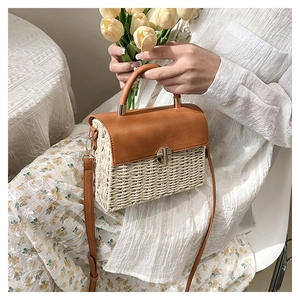 Detailed view of woven straw bag texture with premium brown leather flap and metal lock