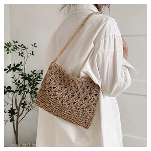 Détail du motif floral tissé main sur le sac en paille porté par un mannequin