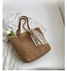 Detail of woven khaki straw tote bag featuring floral lace scarf and rustic texture