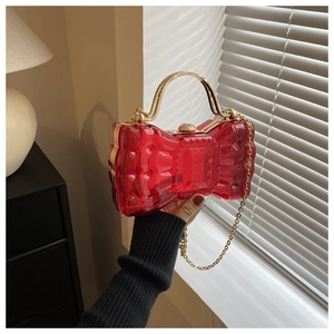 Détail du sac de soirée nœud rouge en acrylique avec chaîne dorée et poignée chic