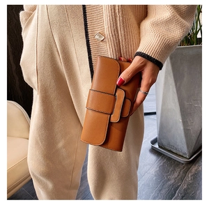 Detail of tan leather long wallet featuring textured grain and classic strap closure