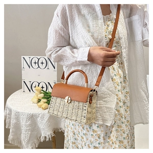 Detail of beige woven crossbody bag with brown leather flap and golden twist lock closure