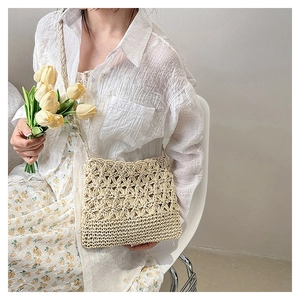 Détail du sac en paille beige tissé main avec motifs floraux et texture crochetée