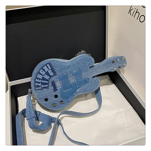 Detail of blue denim guitar cross-body bag with metal studs and embroidery in a gift box