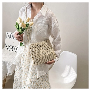 Détail du sac bandoulière en paille tissé main avec motifs fleuris ajourés et fine sangle