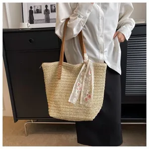 Detail of straw woven tote bag with brown handles and floral lace scarf decoration