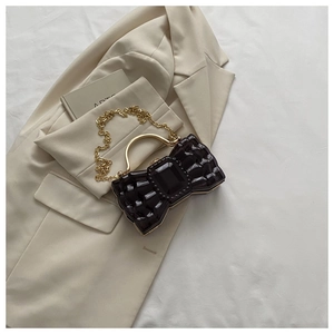 Détail d'un sac de soirée nœud créatif avec pierre noire et poignée en anneau doré