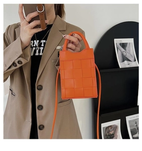 Detail of orange woven mini handbag with wide leather strips and long shoulder strap