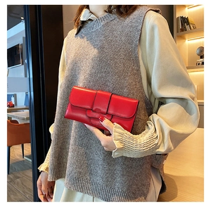 Close-up of a stylish red leather long wallet with buckle detail held by a model