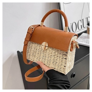 Detail of woven texture with brown leather flap and golden twist lock on shoulder bag