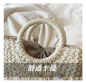 Détail du sac en paille avec doublure à pois et breloque en forme de cœur perlé