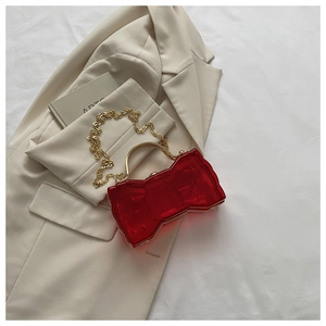 Vue détaillée d'un sac à main en acrylique rouge en forme de nœud avec chaîne dorée chic