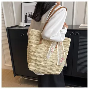 Detail of hand-woven summer straw tote bag with floral embroidery lace ribbon and leather strap