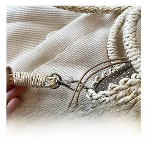 Détail du crochet pivotant argenté et du tissage en paille d'un sac à main beige coquille