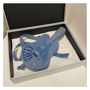 Detail of guitar shaped denim crossbody bag featuring metal rivets and white stitching