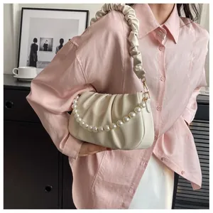 Detail of cream pleated cloud bag with elegant pearl strap and soft PU texture