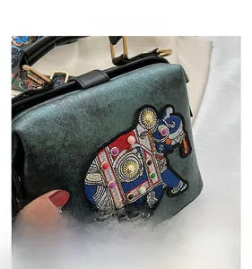 Gros plan de la broderie d'éléphant colorée sur un sac à main vert foncé exotique