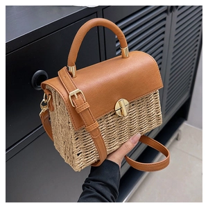 Detail of woven straw and brown leather shoulder bag with gold metal twist lock