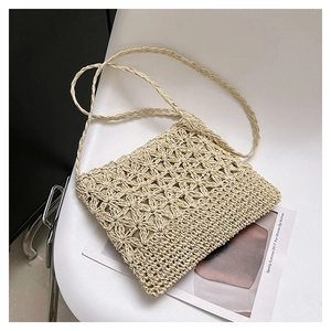 Gros plan du sac bandoulière en paille beige tissé main avec des motifs floraux