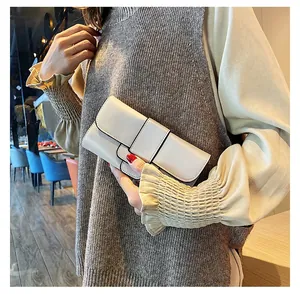 Detail showing the beige minimalist clutch bag with a sleek flap closure and stitching