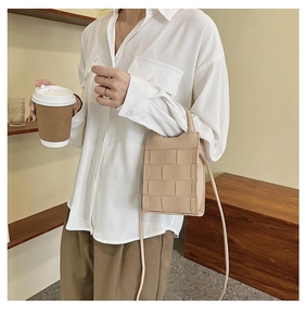 Detail of beige woven leather phone bag texture and shoulder strap on model