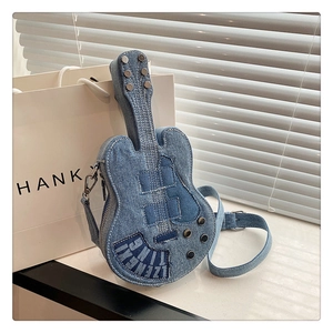 Detailed close-up of blue denim guitar-shaped crossbody bag with decorative metal studs