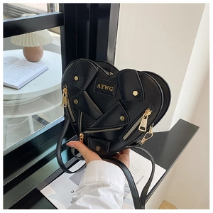 Detail shot of heart-shaped black leather bag with biker jacket zipper and gold hardware