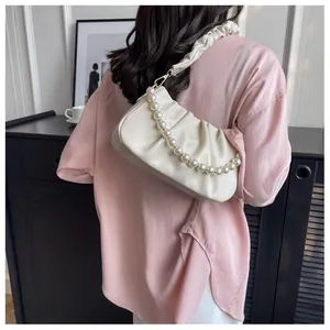 Close-up of beige pleated dumpling bag featuring elegant pearl chain and soft PU leather