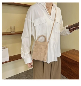 Chic beige woven mini square bag with top handle and strap shown on model in a studio
