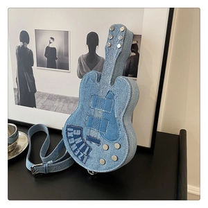 Detail of guitar-shaped denim crossbody bag featuring white stitching and metal rivets