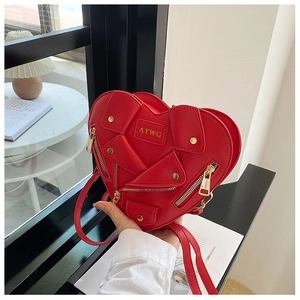 Detailed view of red heart-shaped biker style crossbody bag with metal zippers and studs