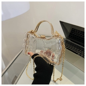 Détail de pochette transparente en acrylique avec poignée dorée et strass décoratifs