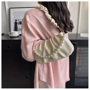 Detail of soft cream pleated cloud bag with elegant pearl chain and wide shoulder strap