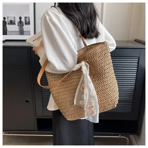 Detail of hand-woven straw tote bag with brown leather straps and floral lace scarf