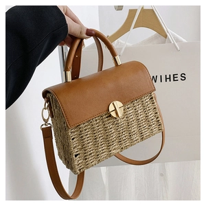 Detail of woven straw and brown leather crossbody bag with a golden circular twist lock