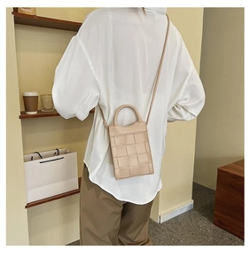 Detail of a beige woven leather mini crossbody bag with a round handle and slim strap