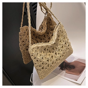 Détail de motifs de fleurs tissés à la main sur sacs bandoulière en paille crème et marron