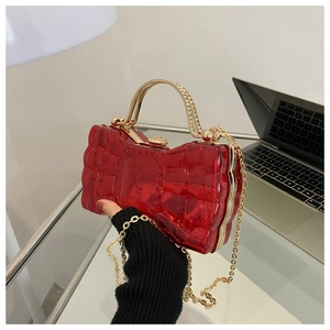 Détail du sac de soirée nœud en acrylique rouge avec chaîne dorée et texture diamant