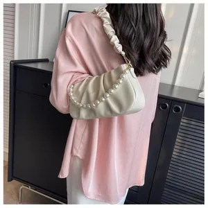 Close-up of soft pleated cloud bag in beige leather with decorative white pearl chain
