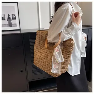 Detail of hand-woven straw tote with leather handles and rose embroidery lace ribbon