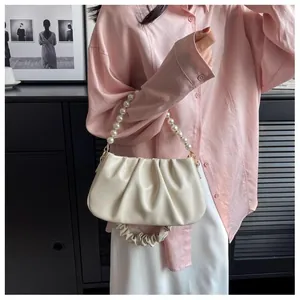 Detail of soft cream pleated cloud bag with elegant pearl handle and gold metal hardware