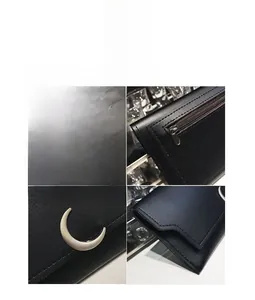 Détail de la boucle lune argentée et de la fermeture éclair sur le portefeuille noir
