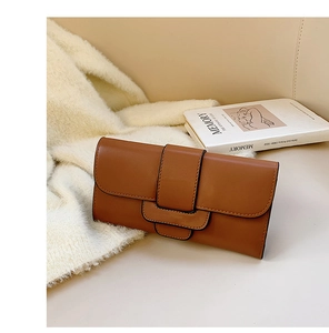 Detail of brown faux leather clutch on knit blanket with stylish decorative book