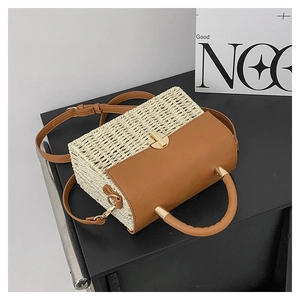 Detail showing the straw woven texture and brown leather flap of the stylish crossbody bag